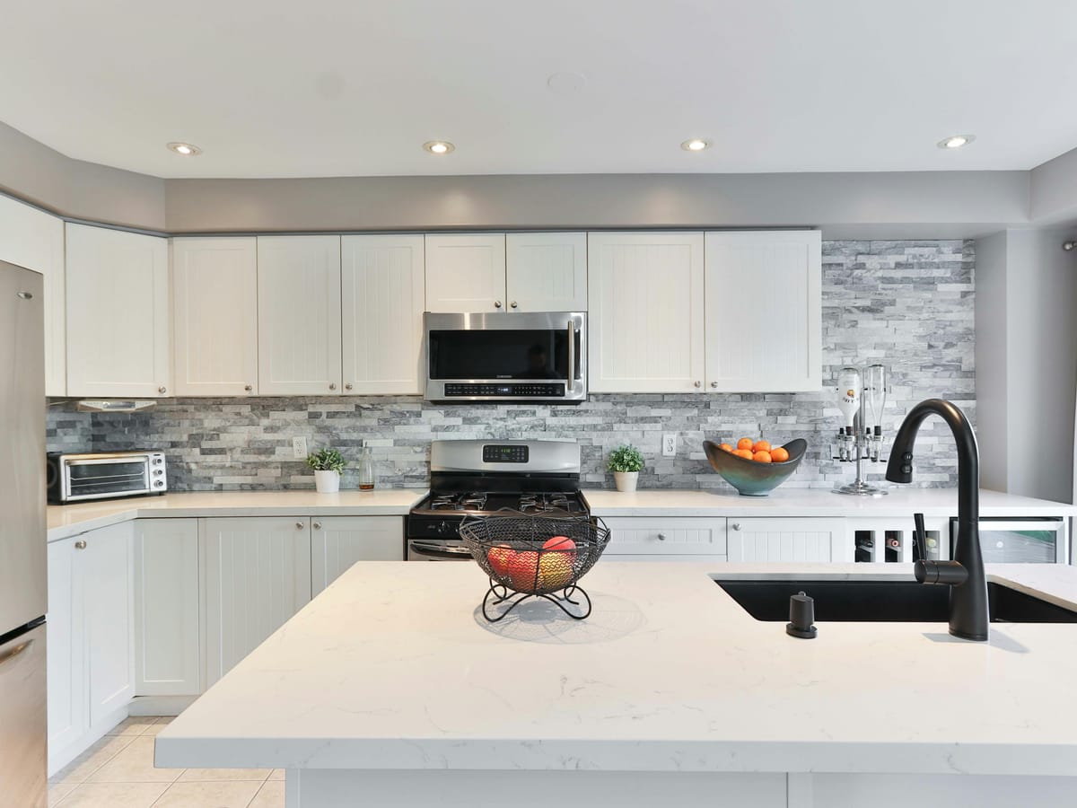 White kitchen with a quartz island and stone backsplash
